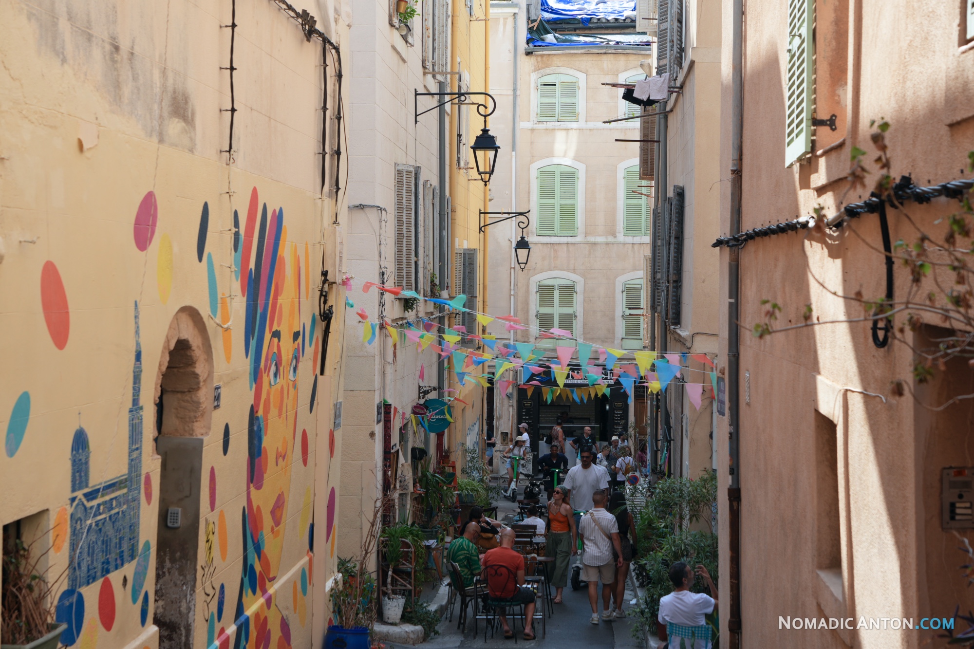 Narrow Le Panier street with colorful wall art, bunting and pedestrians.