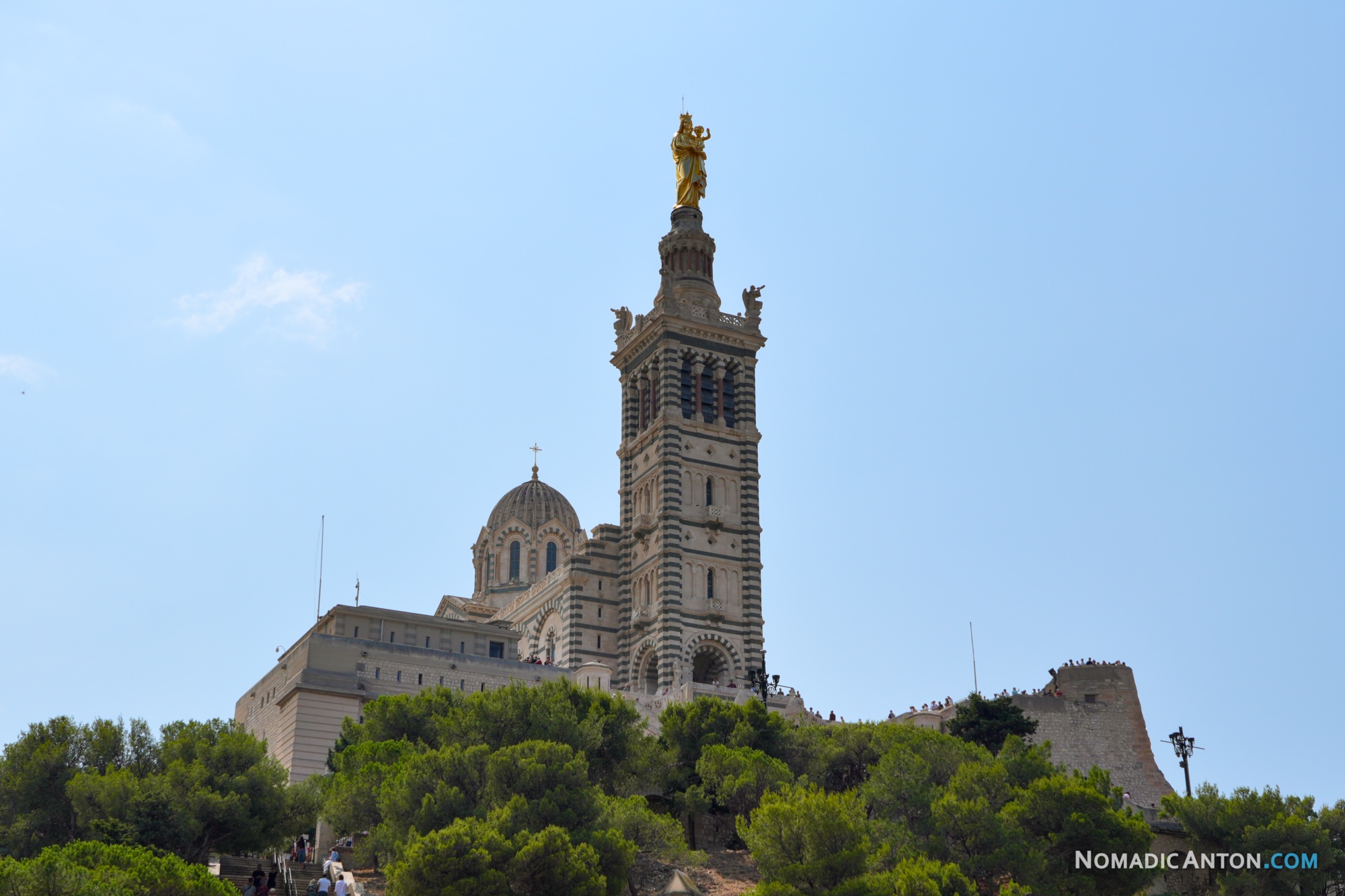 Notre-Dame de la Garde rising above trees in Marseille.