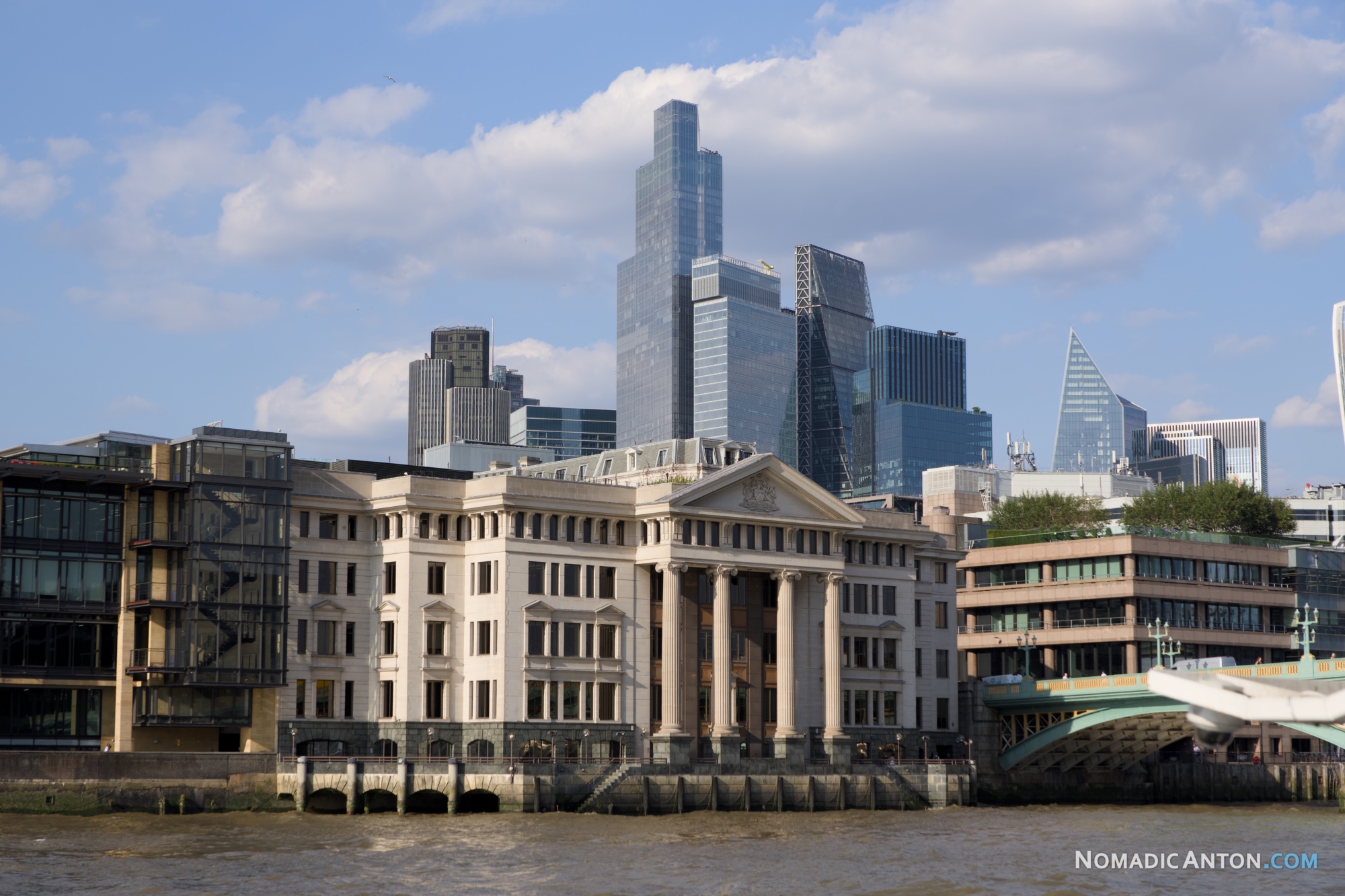 Historic stone building beside modern glass towers along the River Thames